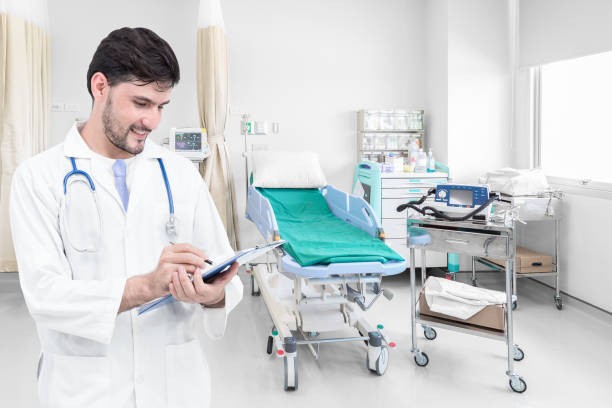B&aacute;c sĩ sử dụng m&aacute;y t&iacute;nh bảng trong ph&ograve;ng bệnh c&oacute; giường bệnh v&agrave; nhiều thiết bị y tế, minh họa hoạt động theo d&otilde;i, quản l&yacute; v&agrave; vận h&agrave;nh trang thiết bị trong bệnh viện.